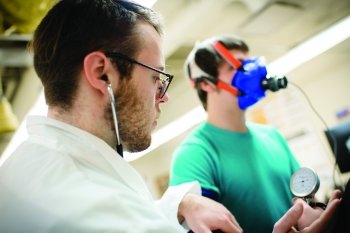 Researcher checking vitals on a suject wearing a mask.