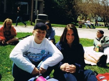 Erika Crook and another person sitting on the grass on campus.