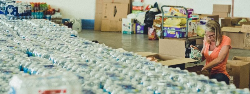 Volunteer sorting through food and water donations.