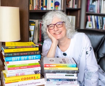 Jennifer Slack at a desk with stacked books.