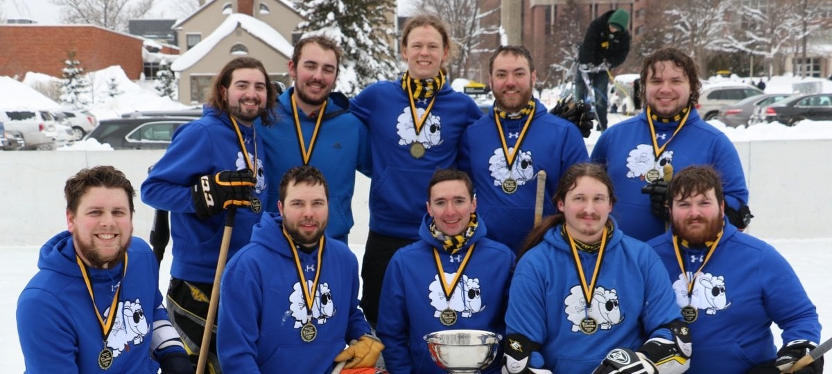 Broomball team with medals and trophy.