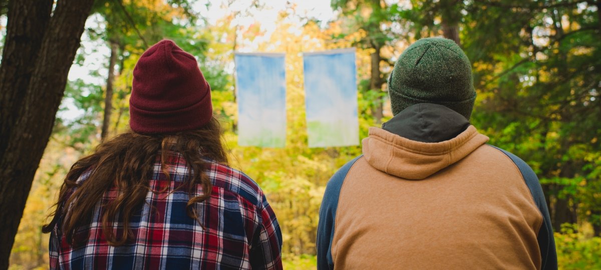 Students sitting in the woods looking at the art.