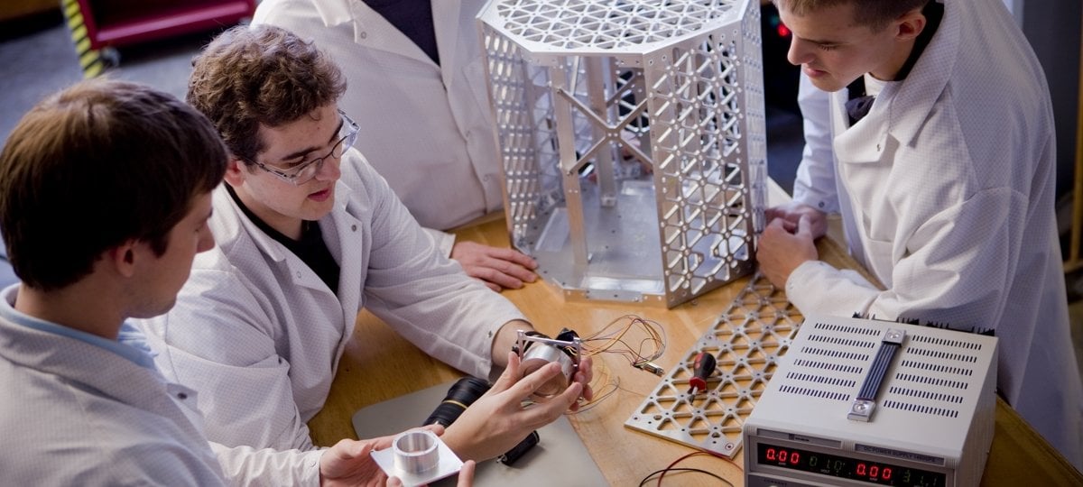 Students at a table working on the satellite.