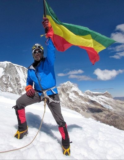 Sirak Seyoum holding a flag on Mount Everest.