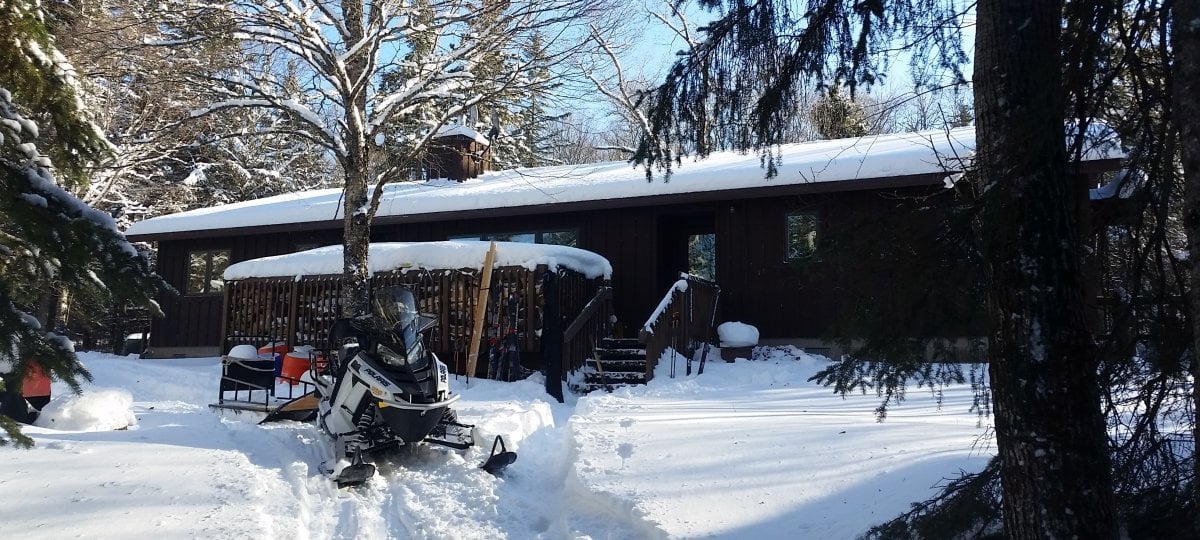 Cabin with a snowmobile in front.