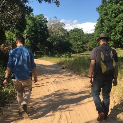 Two people walking down a dirt road.