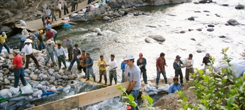 People working on a dam at a river.