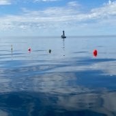 Buoys on the water with a lighthouse in the background.