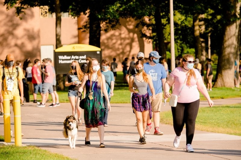 Students wearing masks walking on campus.