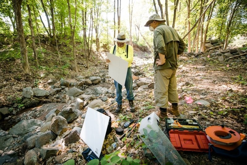 Tim Scarlett works with a student in the woods.