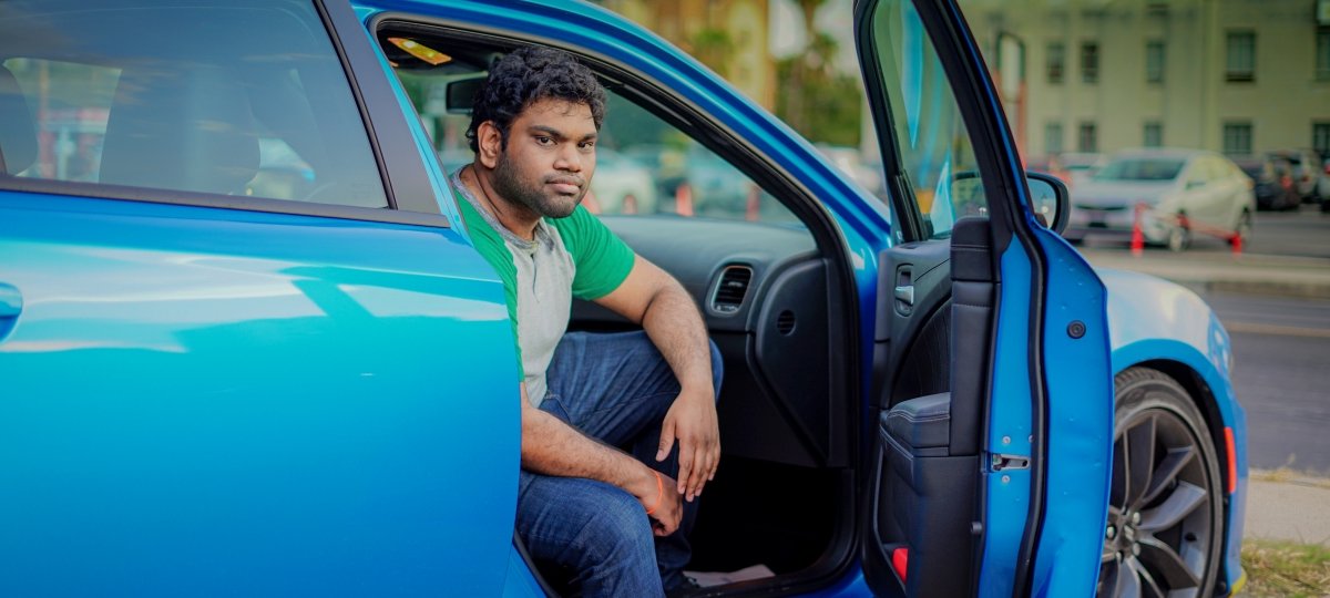 Man sitting in a car with the door open.