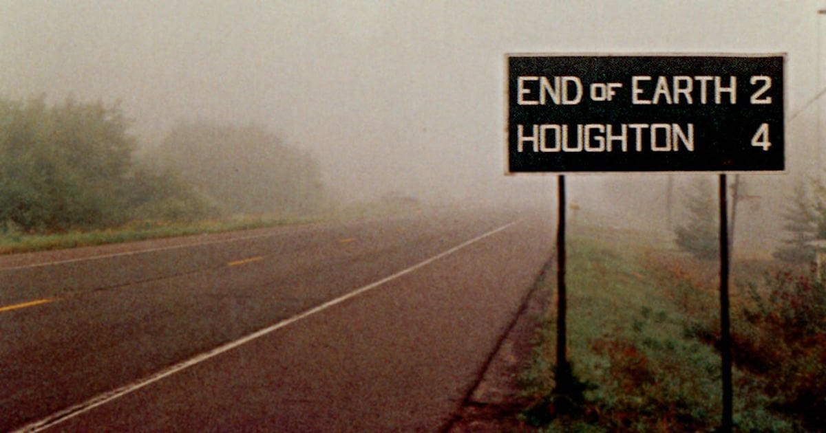 Foggy road with sign showing End of Earth 2 miles, Houghton 4 miles.