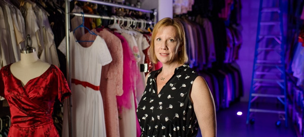 Mary Cyr standing in front of racks of clothing.