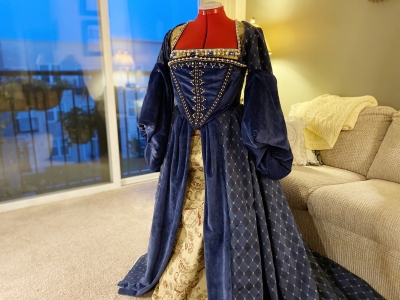 A blue Tudor gown with red neck on a mannequin.