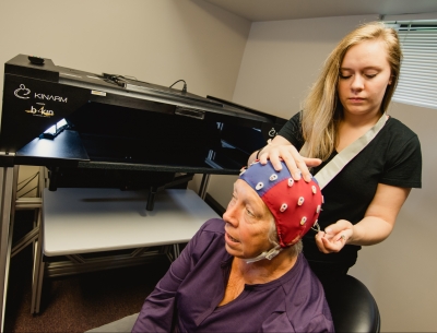 Researcher fitting a cap with electrodes on a person.