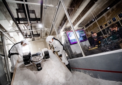 Two researchers testing the lunar rover in the lab while two more watch.