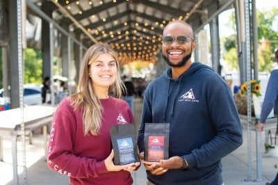 Arick and Sarah each holding a bag of coffee.