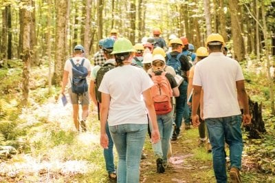 Students in hard hats walking through the forest.