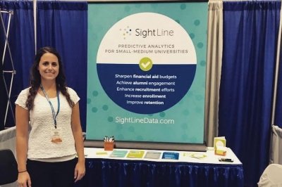 Ashley standing next to her SightLine conference booth.