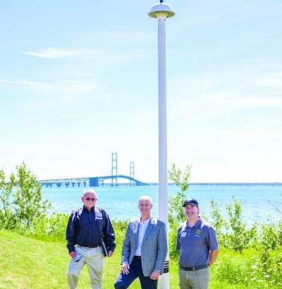 Three men standing next to the radar tower.