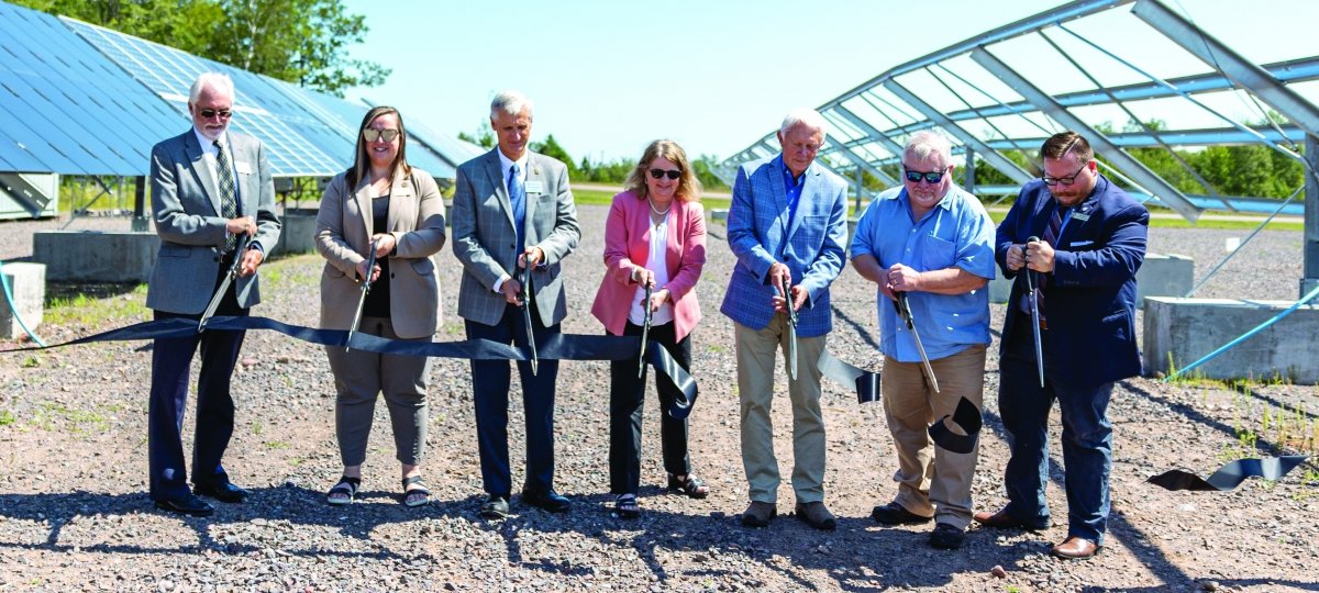 Seven people cutting a black ribbon at the Solar Energy RTC.