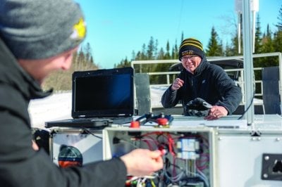 Paul and a student test the rover outside in the snow.