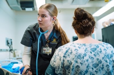 Nursing student practices taking a person's blood pressure.