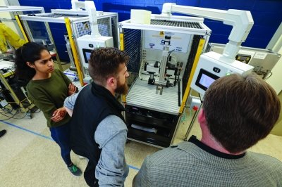 Professor Sergeyev showing two students a piece of equipment in the mechatronics lab.