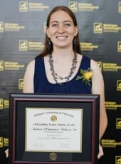 Andrea Falasco holding the framed award certificate.