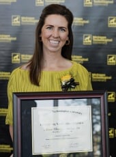 Anne Dancy Maher holding the framed award certificate.