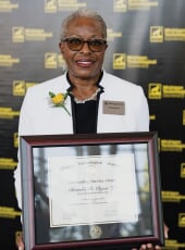 Brenda Ryan holding the framed award certificate.