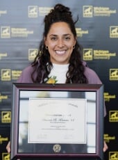 Danna Kasom holding the framed award certificate.