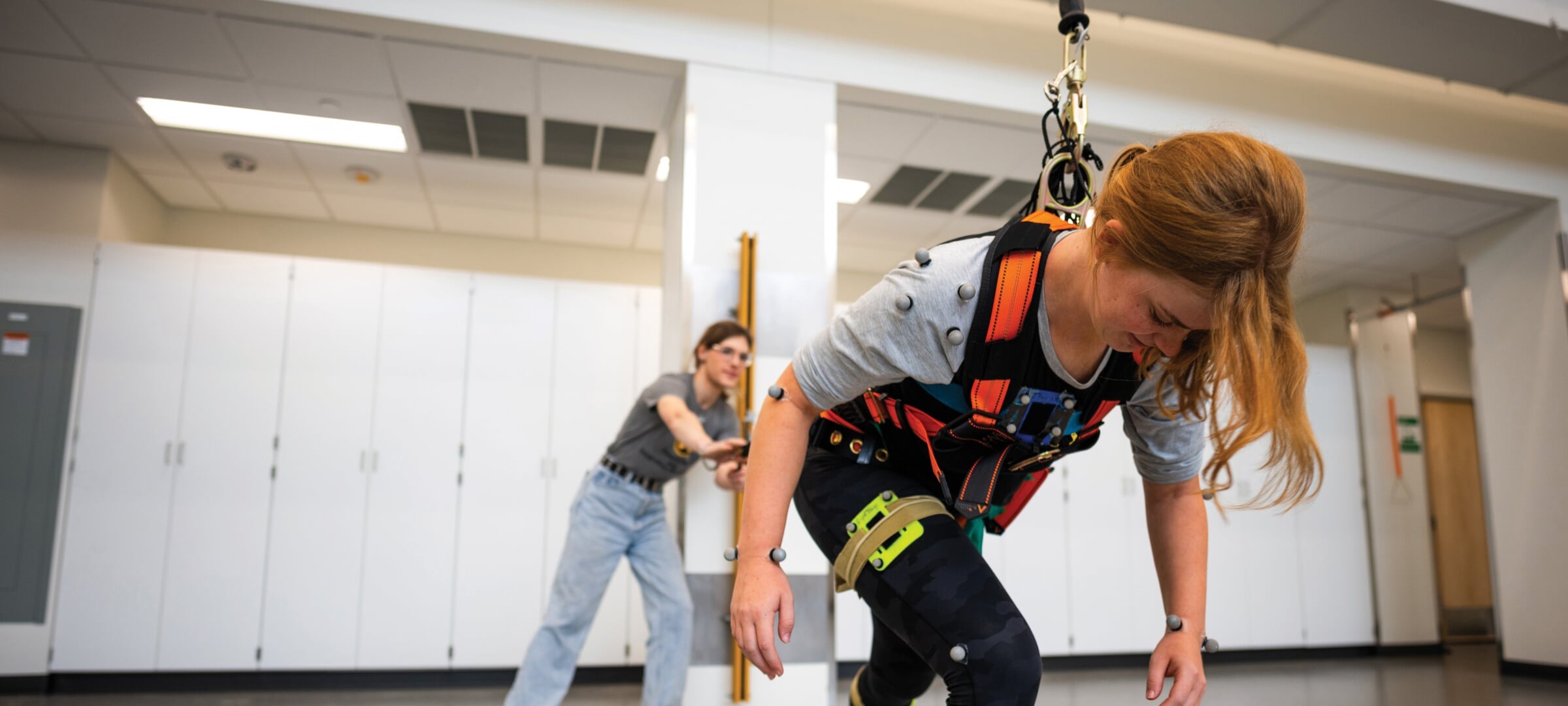 Researcher observing person in a harness falling forward.