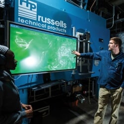 Researcher points to a screen with a russells technical products logo above it.
