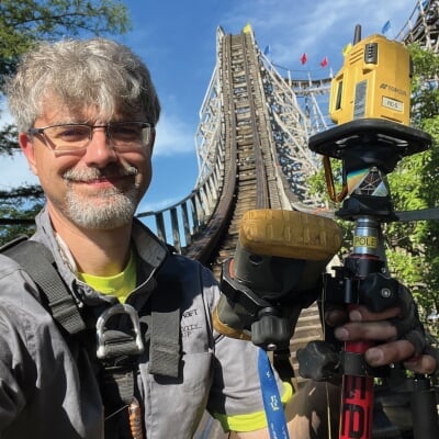 Korey Kiepert holding equipment while walking on a wooden roller coaster.
