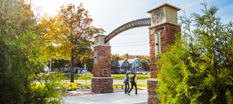 Students walking under the alumni gateway on campus.
