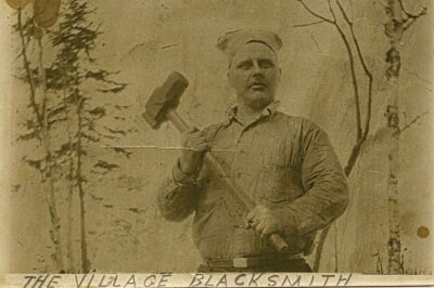 Old sepia-toned photo of a man holding a sledgehammer.