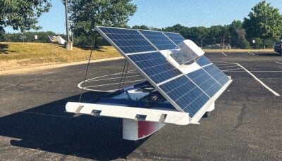 Solar car in a parking lot with it's cover propped open.