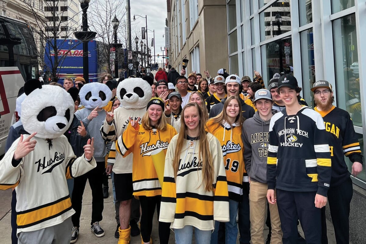 Group of students in Michigan Tech apparel, including three with panda heads on.
