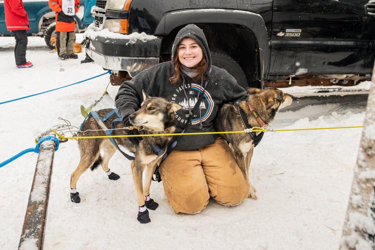 A Mushing Club student with her arms around two of the dogs.