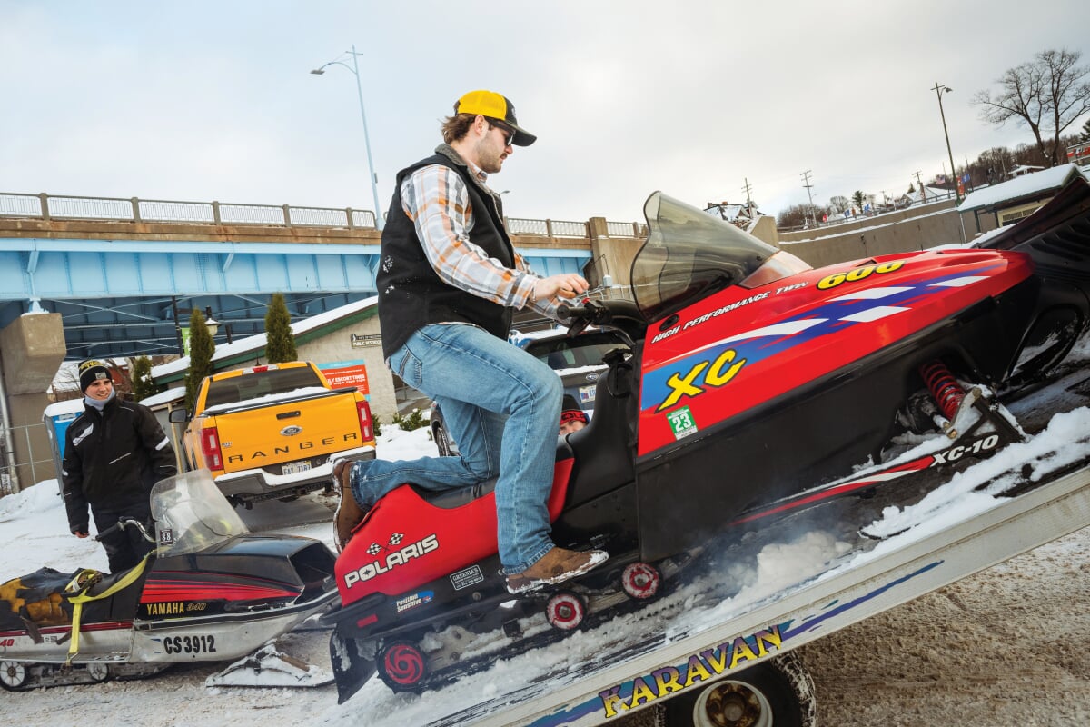 One person loading their red snowmobile on a trailer.