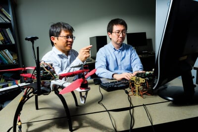 Bo Chen and Niusen Chen at a computer with a drone on the desk.
