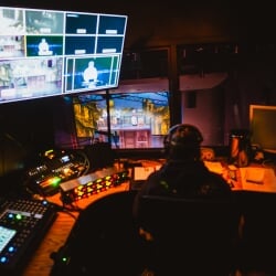 Lighting technician in the light booth above the theater watching the play and adjusting lights.