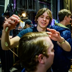 Stage hand getting an actor fitted with a microphone.