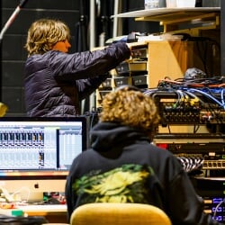 Two students working at a computer and sound board with lots of wires.