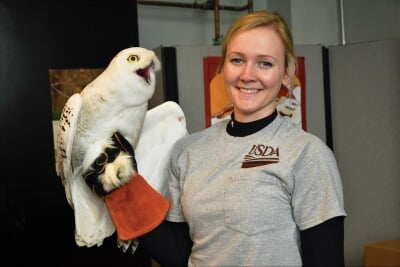 Megan Baker wearing a USDA shirt and holding a large white bird.