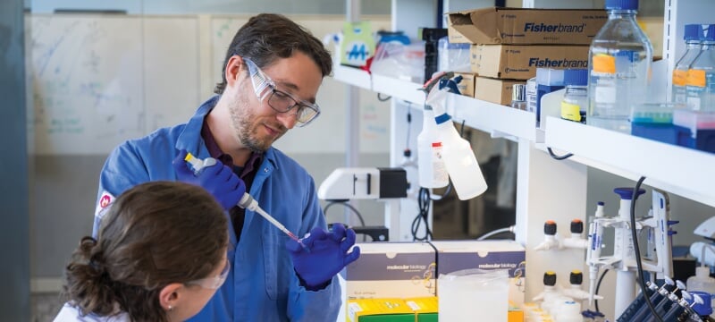 Paul Goetsch working with a sample in the lab while a student watches.