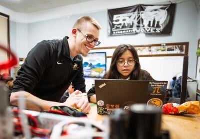 Edwin Yazbec standing next to a student looking at a laptop.