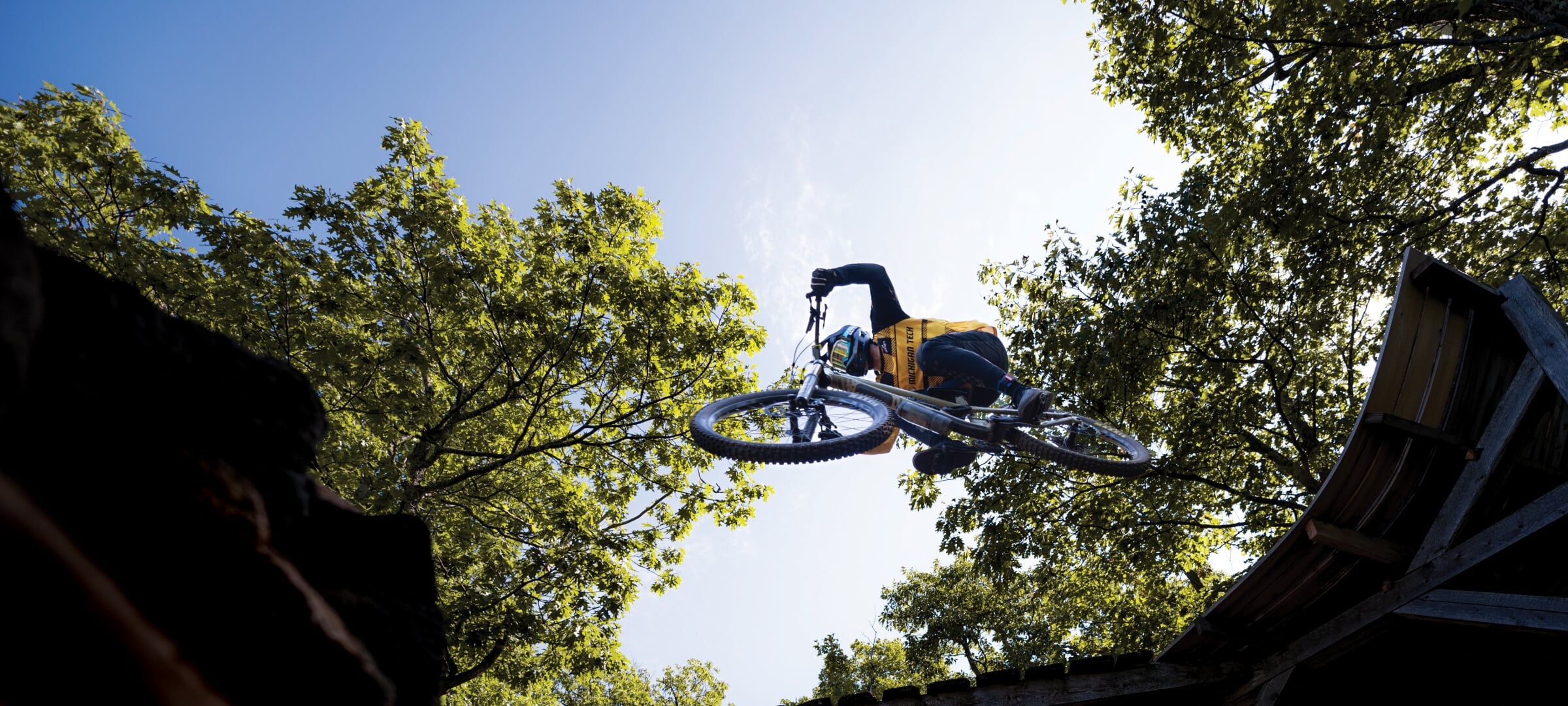 Person on a mountain bike overhead as they jump a feature on the trail.
