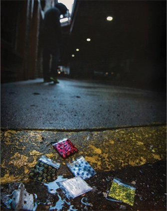 Colorful baggies filled with unknown substances sitting on a wet curb